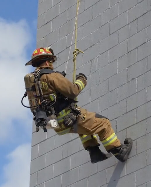 Firefighter suspended on the side of a building